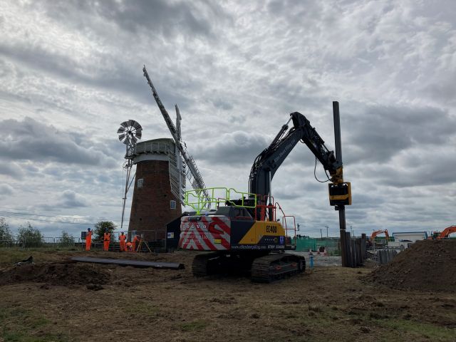 Horsey Outfall Piling in June25 Excavator carrying out work and windpump in background